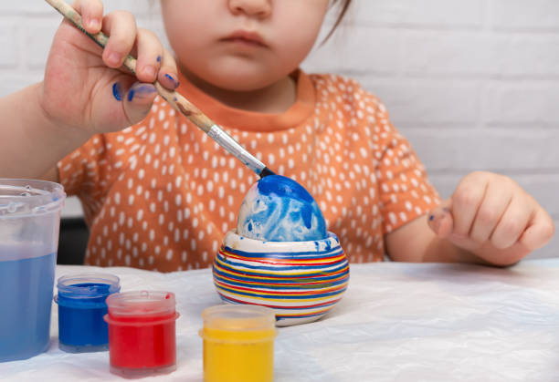 A little girl paints eggs for Easter. Preparation for the Easter holidays.