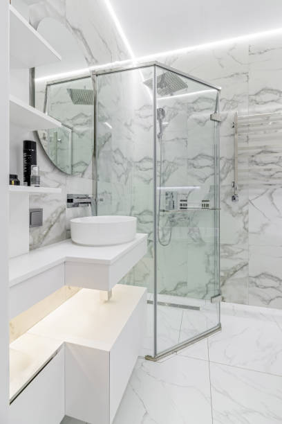 istock Simple white painted bathroom with lozenge shaped bath, glazed panel shower cubicle 2012310912