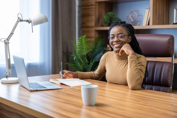 istock Cheerful woman with dreadlocks works remotely using laptop and technology 2012327648
