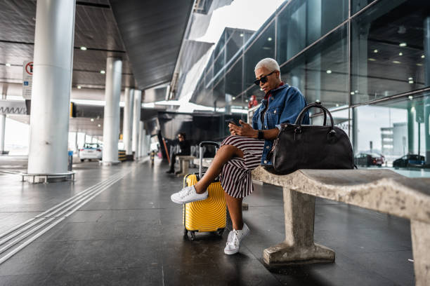 Mature woman using mobile phone while wait at airport
