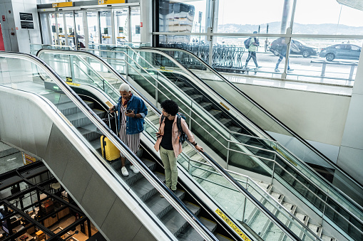 Mid adult couple moving down on escalator at airport