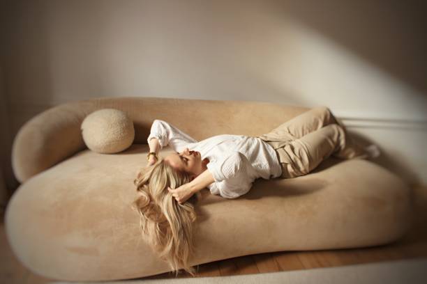 istock A beautiful blonde is posing on a beige sofa in sunlight 2012360260