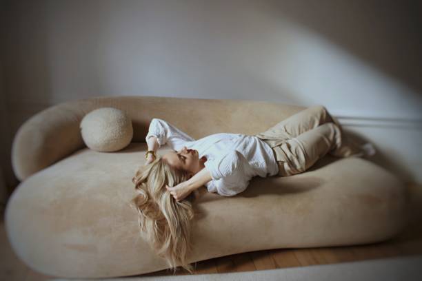 istock A beautiful blonde is posing on a beige sofa in sunlight 2012365089