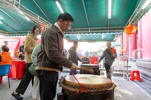 2024 Feb 11,Hong Kong.A Worshipper beating the drum for good fortune at Che Kung Temple