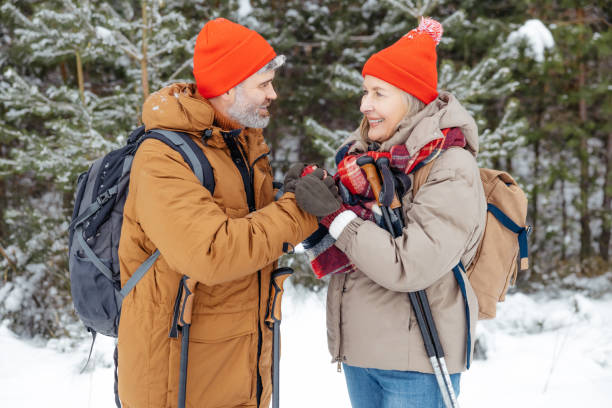 istock Man warming up his wifes hands while having a walk in a winter forest 2012386591