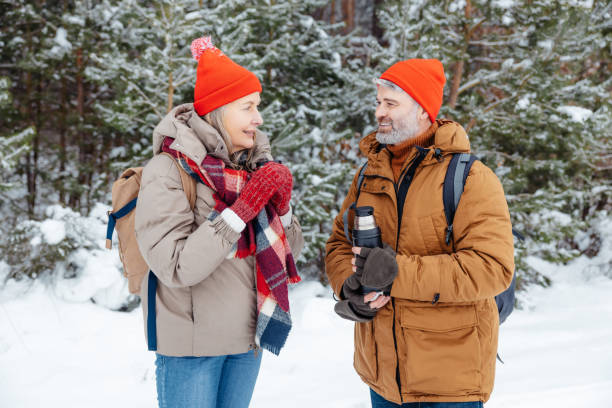 istock Smiling mature couple having hot tea in a winter forest 2012386611