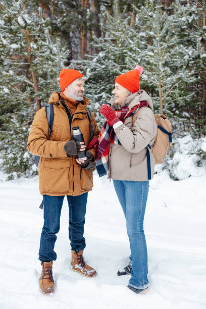 istock Smiling mature couple having hot tea in a winter forest 2012386612