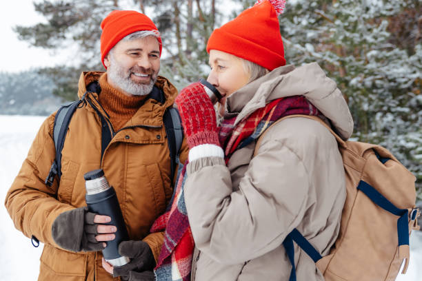 istock Smiling mature couple having hot tea in a winter forest 2012386622