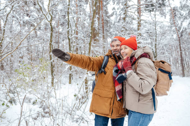 istock Man and woman in warm clothes spending time in a winter forest 2012386721