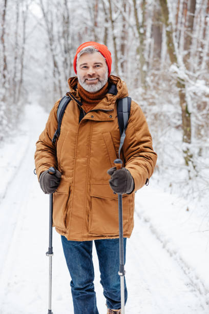 istock Mature bearded man with scandinavian walk sticks in a winter forest 2012386747