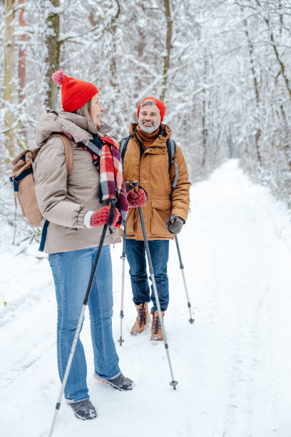 istock Mature couple having a walk in a snowy forest with scandinavian sticks 2012386748