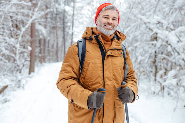 istock Smiling mature man in red hat in a snowy forest 2012386779