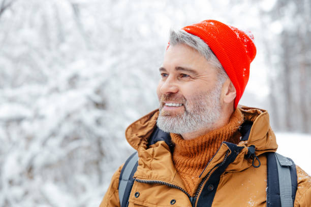 istock Mature caucasian man in red hat on a snowy background looking contented 2012386780