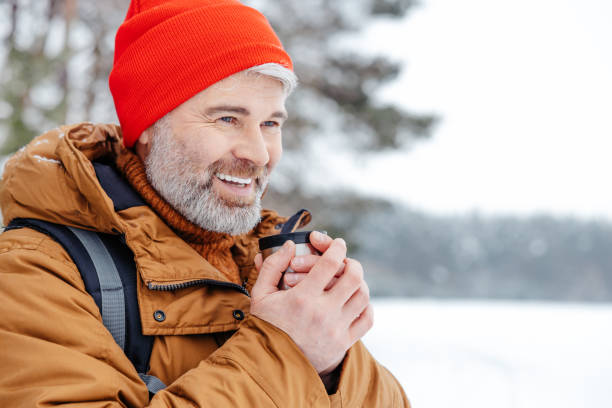istock Man with thermos in hands in a snowy forest 2012386797