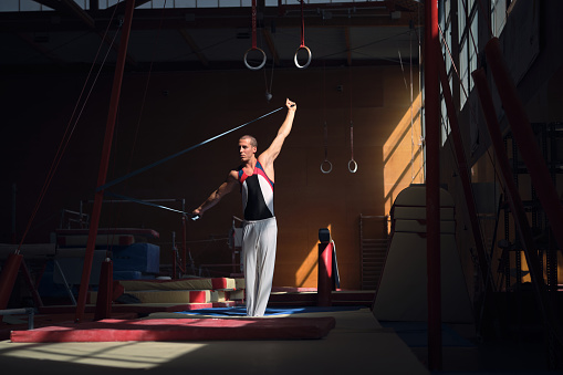 Young sports gymnast stretching with a rubber band in the gymnasium before doing her exercises.