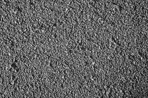 A detailed close-up photo capturing the gritty texture of urban asphalt, highlighting the rugged beauty of a well-traveled city road.