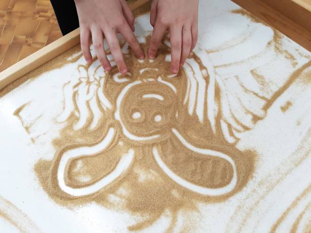 istock A girl draws a bunny on a light table. Drawing sand. 2012438116