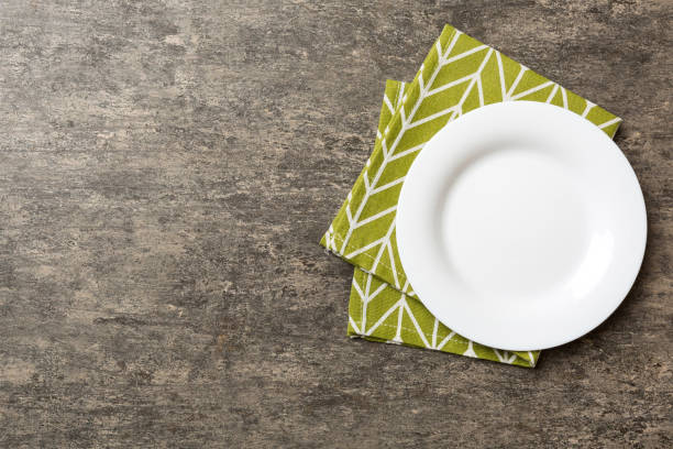 istock Top view on colored background empty round white plate on tablecloth for food. Empty dish on napkin with space for your design 2012438168