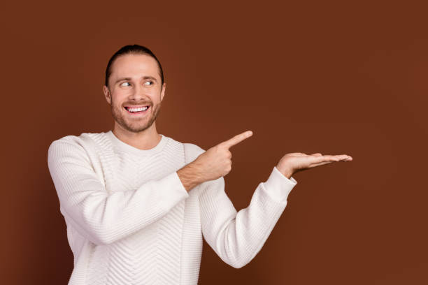 istock Photo of dreamy funky guy dressed white pullover looking pointing finger showing arm empty space isolated brown color background 2012440920