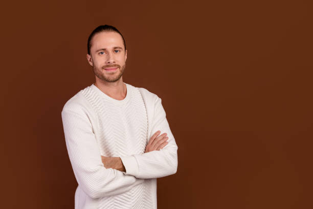 istock Photo of cheerful good mood guy dressed white pullover arms folded empty space isolated brown color background 2012440921
