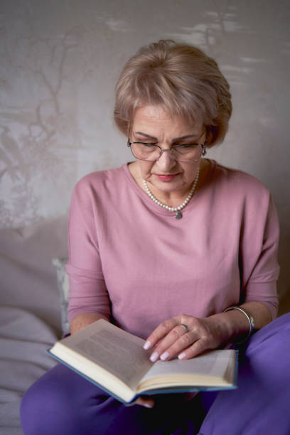 istock elderly woman reads a book at home 2012445282