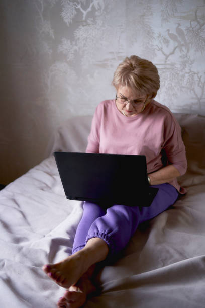 istock an elderly woman works with laptop at home 2012445303