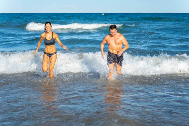 istock Middle aged couple exercising together on the beach this summer 2012454960