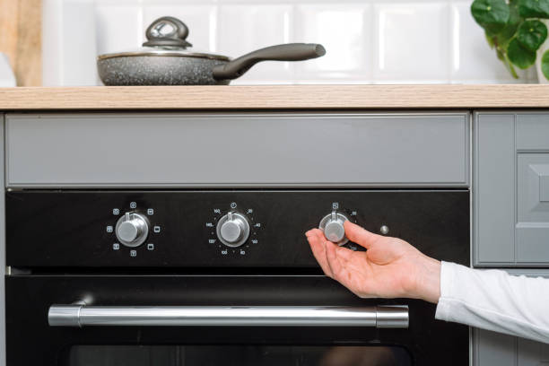 istock Closeup on female hand turn on electric oven on modern kitchen 2012461819