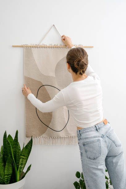 istock Woman hangs handmade macrame with ethnic ornament on the wall 2012462909