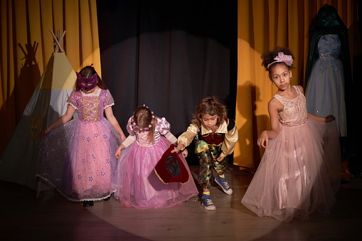 Full length portrait of group of children taking final bow on stage in school play production