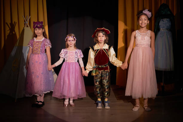 Center of attention. Ballerina standing on stage in theatrical light with red curtains. Concept of focus, individuality, creative discipline used for editorial and educational visuals.