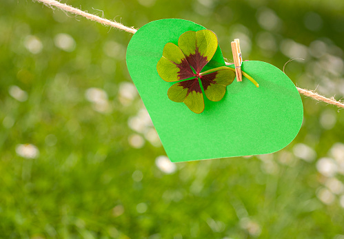 A heart with lucky clovers is clinging to a rope