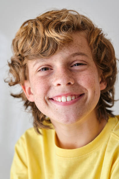 istock Smiling boy with brown hair on light background 2012498205