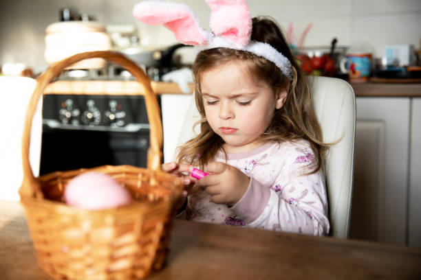 istock Little beautiful girl with easter bunny ears on with her basket of easter eggs. Happy Easter holiday. 2012503671