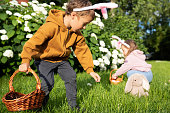 Cute boy and girl celebrating Easter, searching eggs. Happy kids laughing, smiling and having fun.