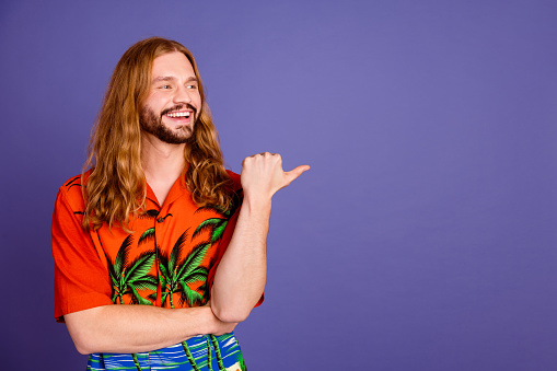 Photo of cheerful person with long hairstyle dressed print shirt look directing at promo empty space isolated on violet color background.