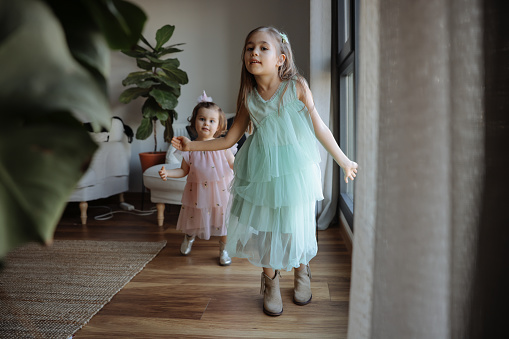 Two small girls dancing together in the living room