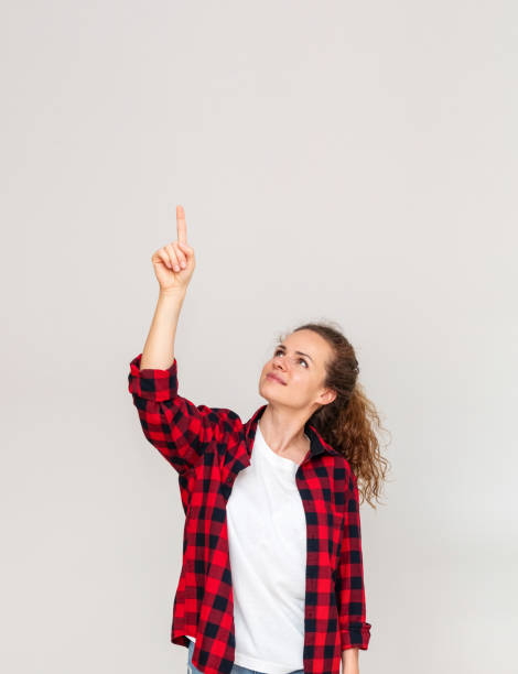 istock Young woman pointing finger up or touching virtual screen with finger. 2012548493