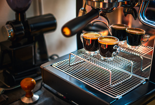 Professional espresso machine while preparing two espressos shot glass in a coffee shop. Espresso shot with coffee crema