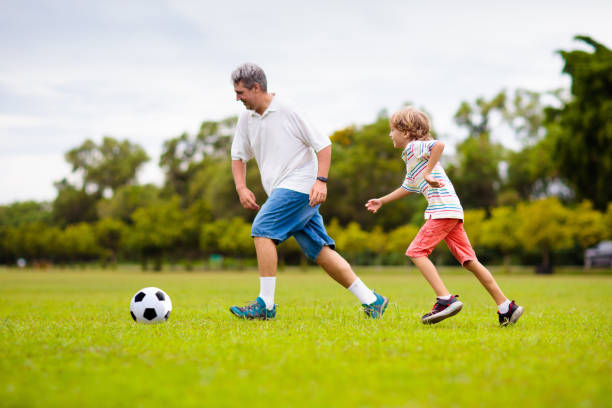 father and son play football. dad and kid run. - 24425 stock-fotos und bilder