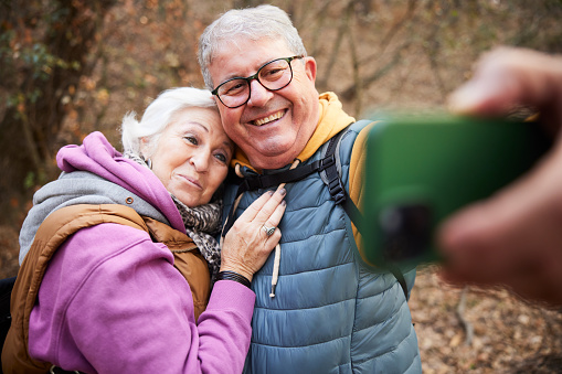 Senior couple shares joy as they take a selfie together while hiking.