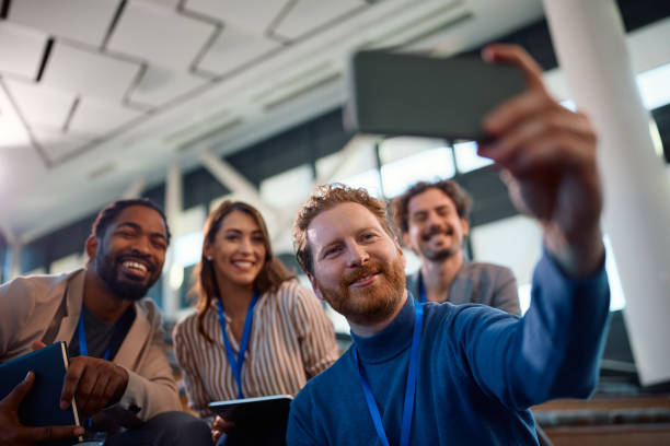 Happy business people taking selfie while attending a seminar in conference hall.