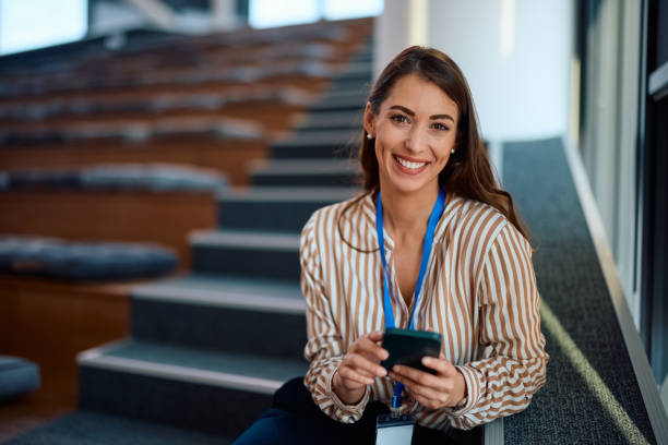 istock Happy businesswoman using cell phone in empty conference hall and looking at camera. 2012571992