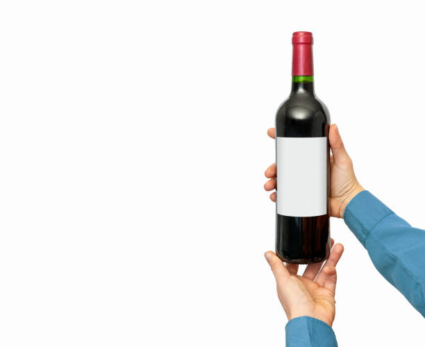 istock Isolated wine bottle with empty label mockup in female's hands. 2012576263