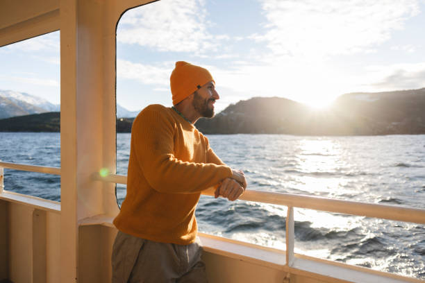 istock man leaning on ferry railing looking at the sea at sunset 2012592986