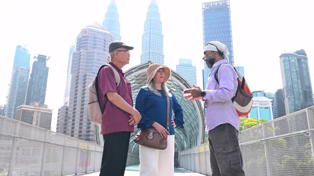 A private Sikh tour guide and two senior Asian traveler walking through the famous Saloma Bridge landmark in the city of Kuala Lumpur, Malaysia