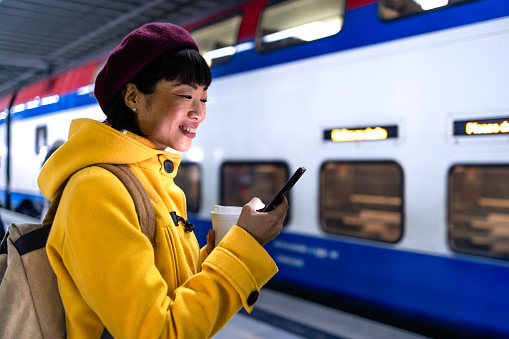 Beautiful Japanese woman at train station platform using mobile phone.