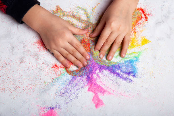 istock Child hands playing with rainbow colored sand. Motor skills, child creativity concept 2012625174