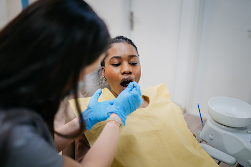 Dentist's assistant wiping modern dental equipment in front of her patient