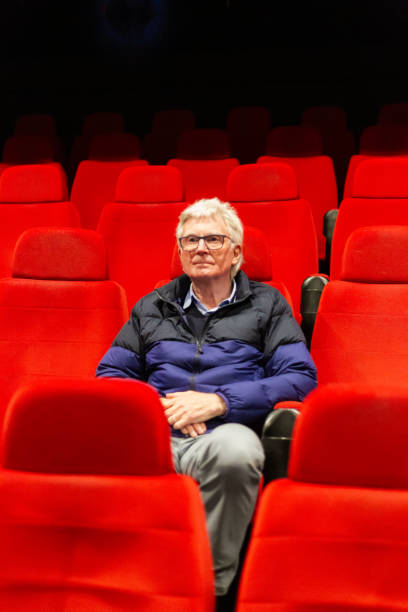 istock Senior man sitting alone in empty movie theater 2012651251